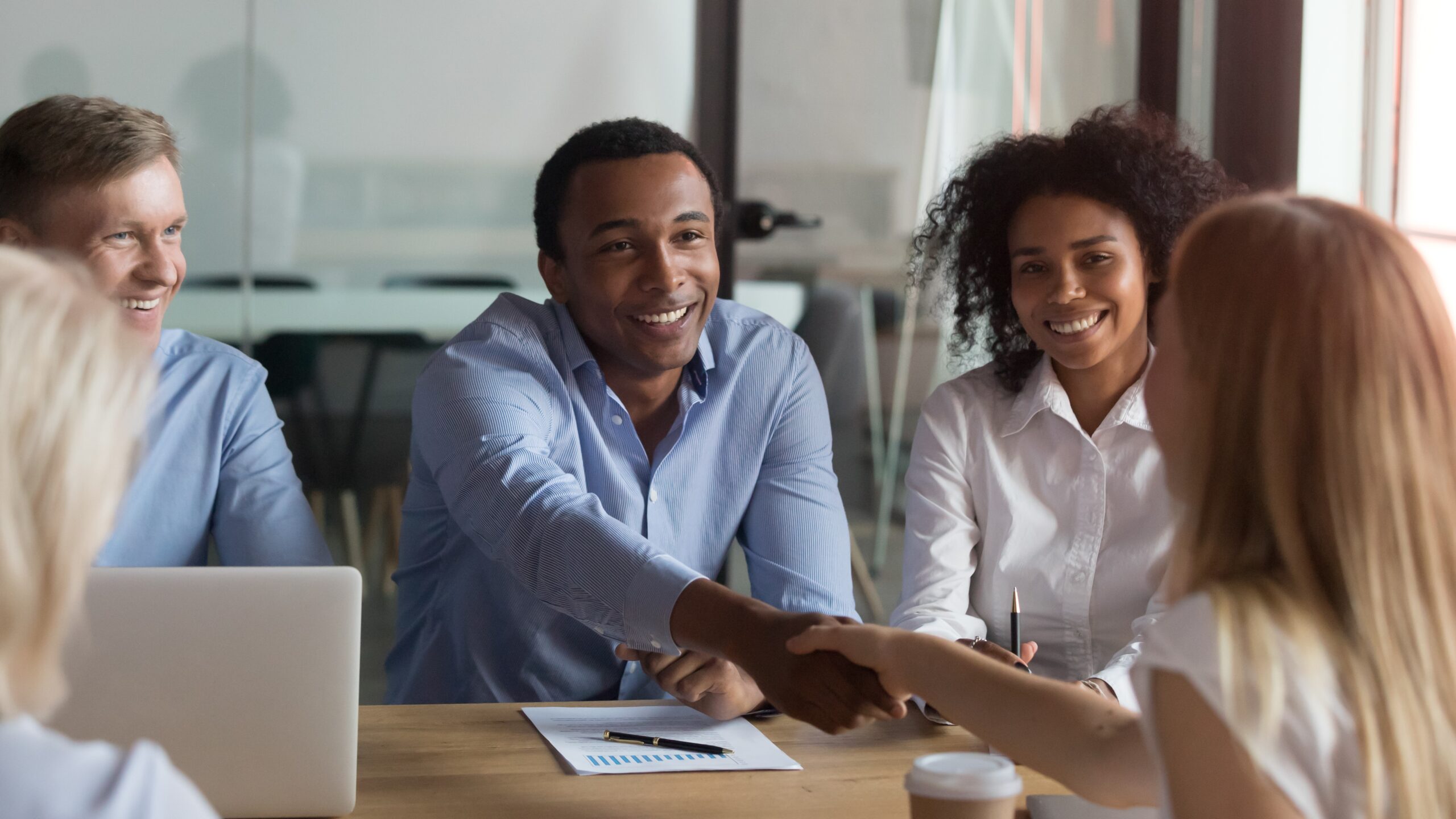 Group of business professionals shaking hands across a table